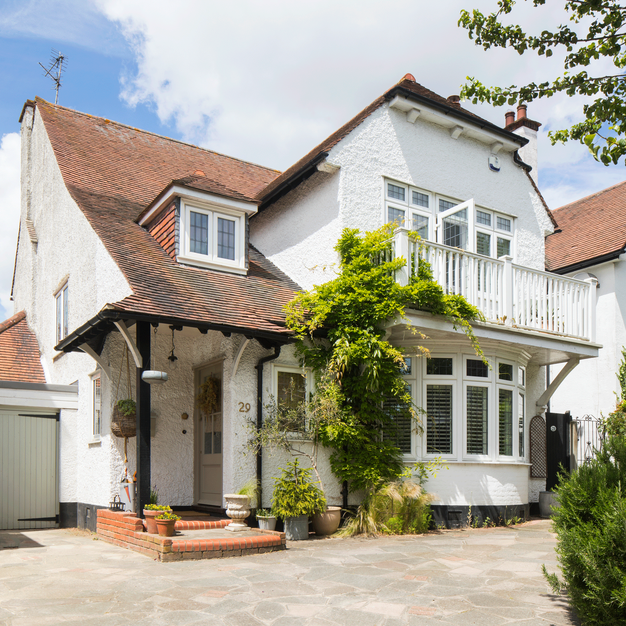 the exterior of a house with a first floor balcony and climbing plants