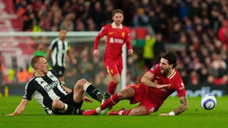 Newcastle United's Dan Burn battles with Liverpool's Dominik Szoboszlai during the Premier League match between Liverpool and Newcastle United at Anfield in Liverpool, England, on February 26, 2025.