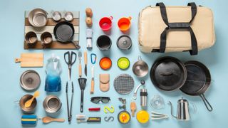 Camping equipment laid out, including cooking utensils and pans