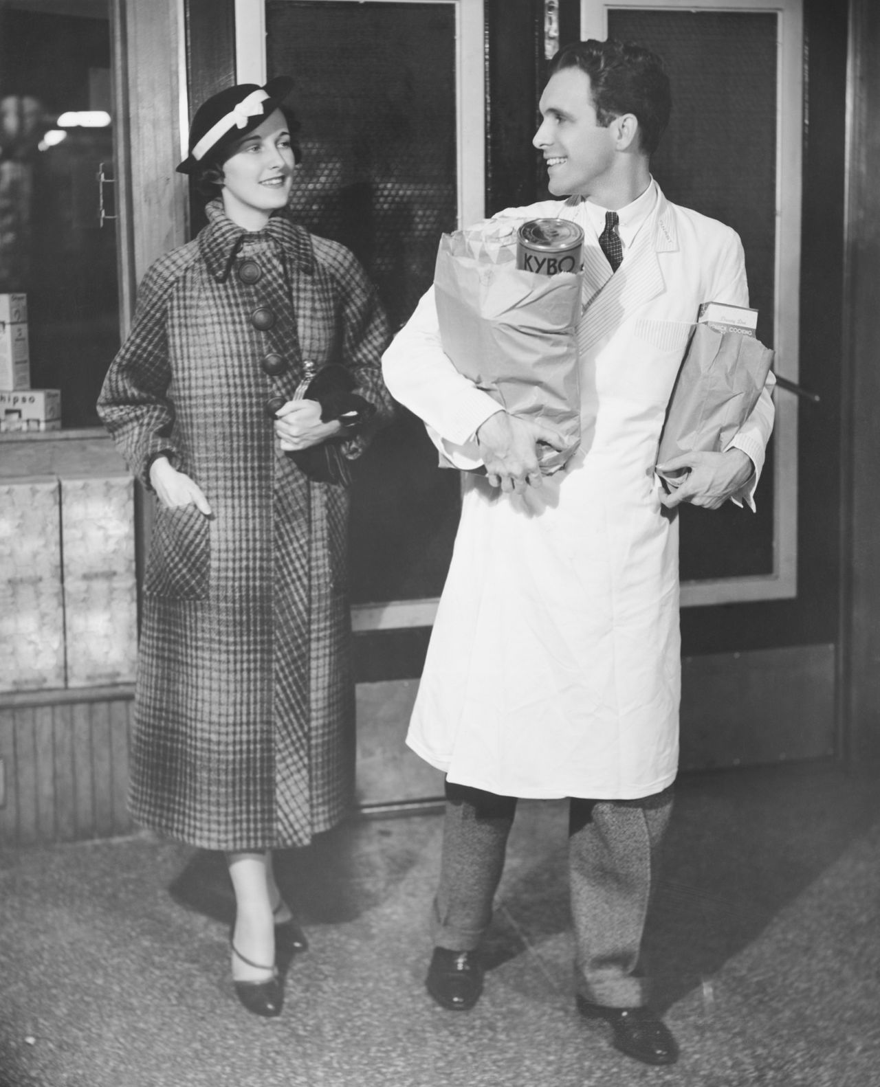 A grocer helps a woman carry her purchases