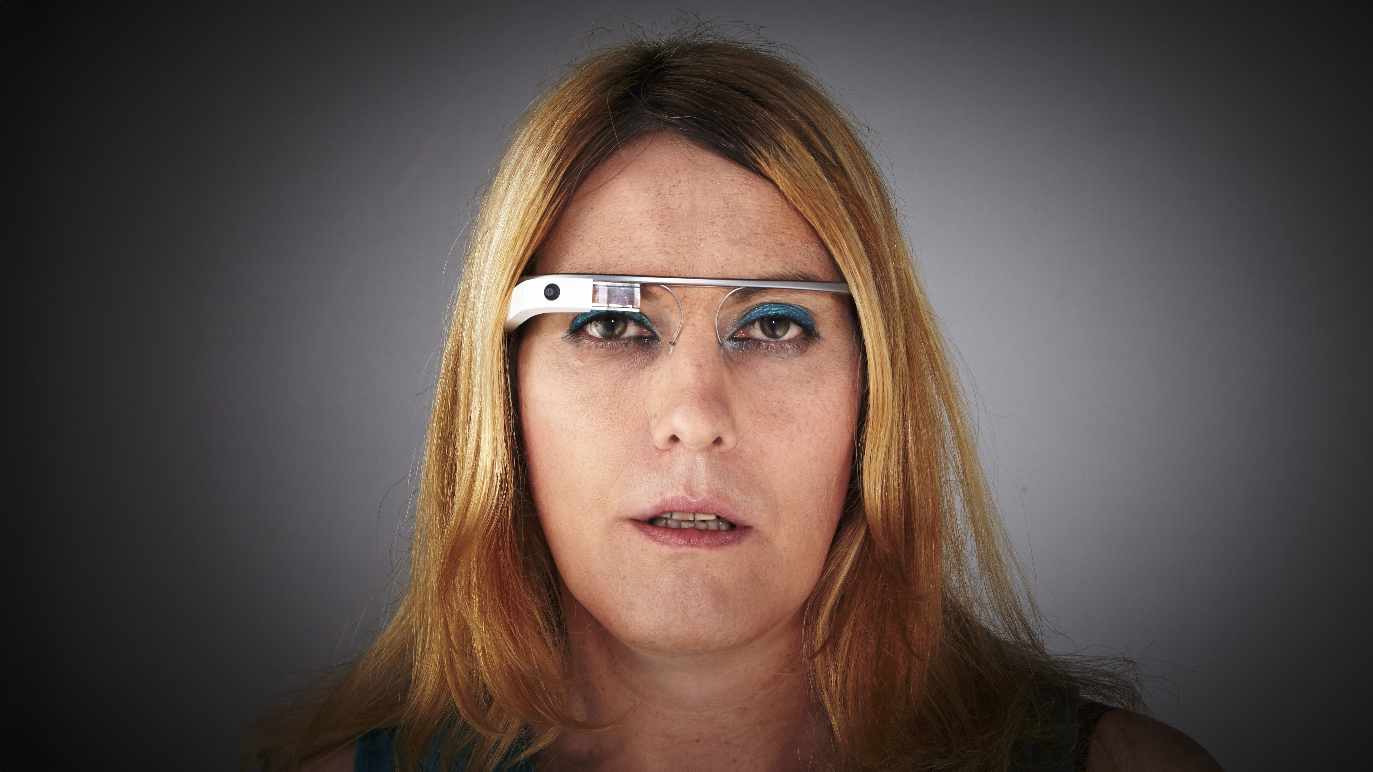 A person wearing Google Glass in front of a dark background