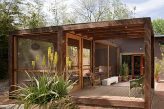 screened-in porch on a wood decking in a modern ranch setting with wicker chairs
