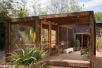 screened-in porch on a wood decking in a modern ranch setting with wicker chairs