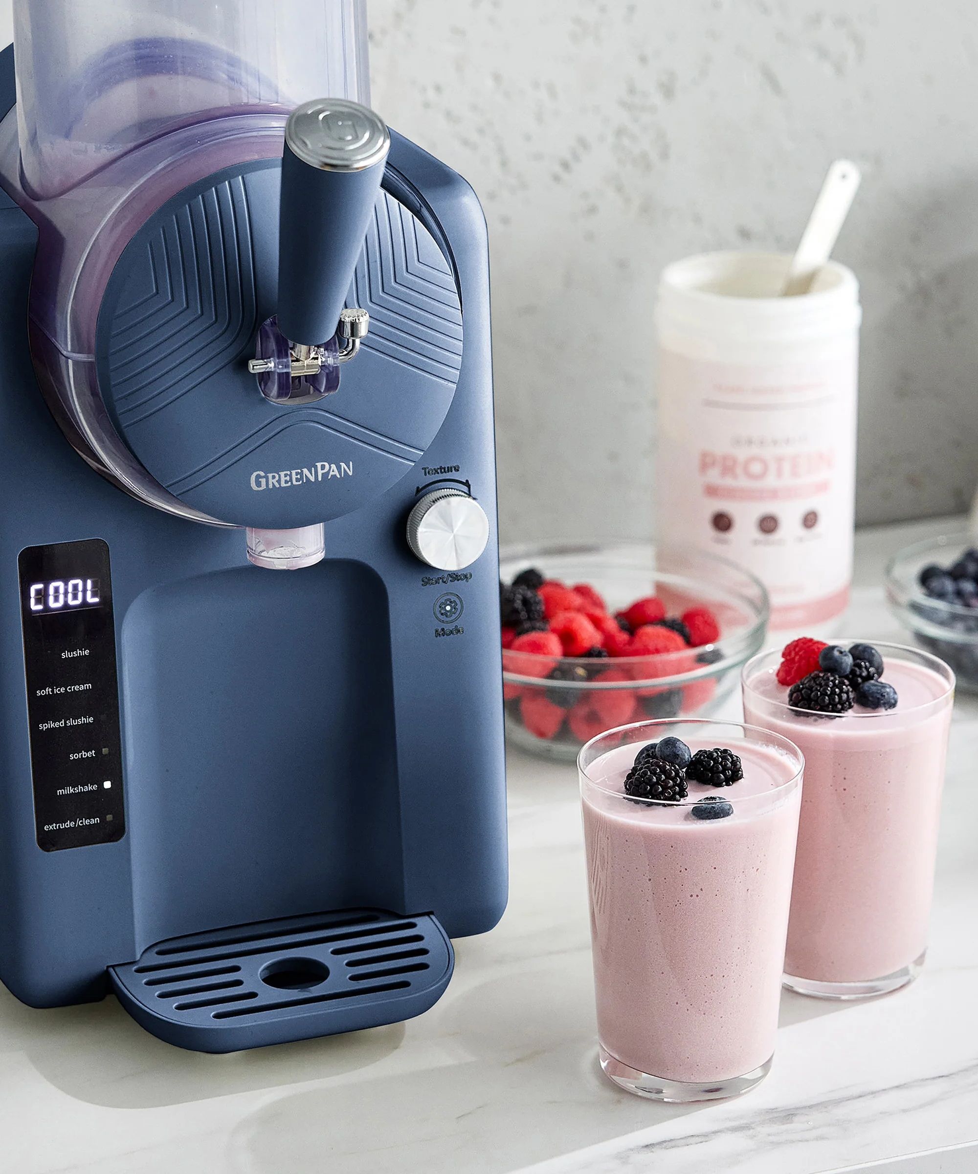 Deep purple ice cream maker with fountain handle, with two strawberry smoothies beside it