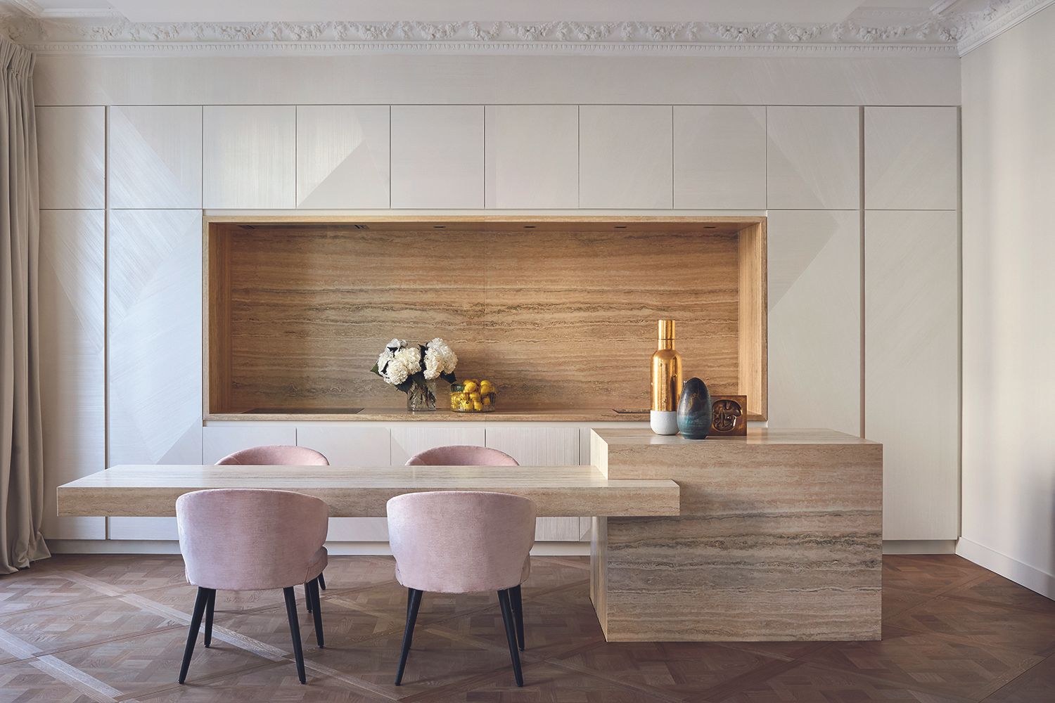 A minimalist kitchen with white concealed cabinets and dusky pink velvet chairs