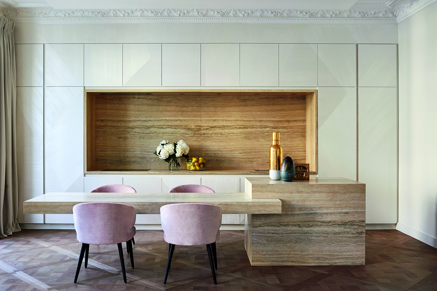 A minimalist kitchen with white concealed cabinets and dusky pink velvet chairs