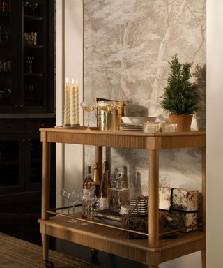 Wooden bar cart with candles, glasses, plates and festive decor