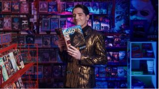 Fangoria Chainsaw Awards host David Dastmalchain in a video store wearing a shimmering gold suit and holding an issue of Fangoria