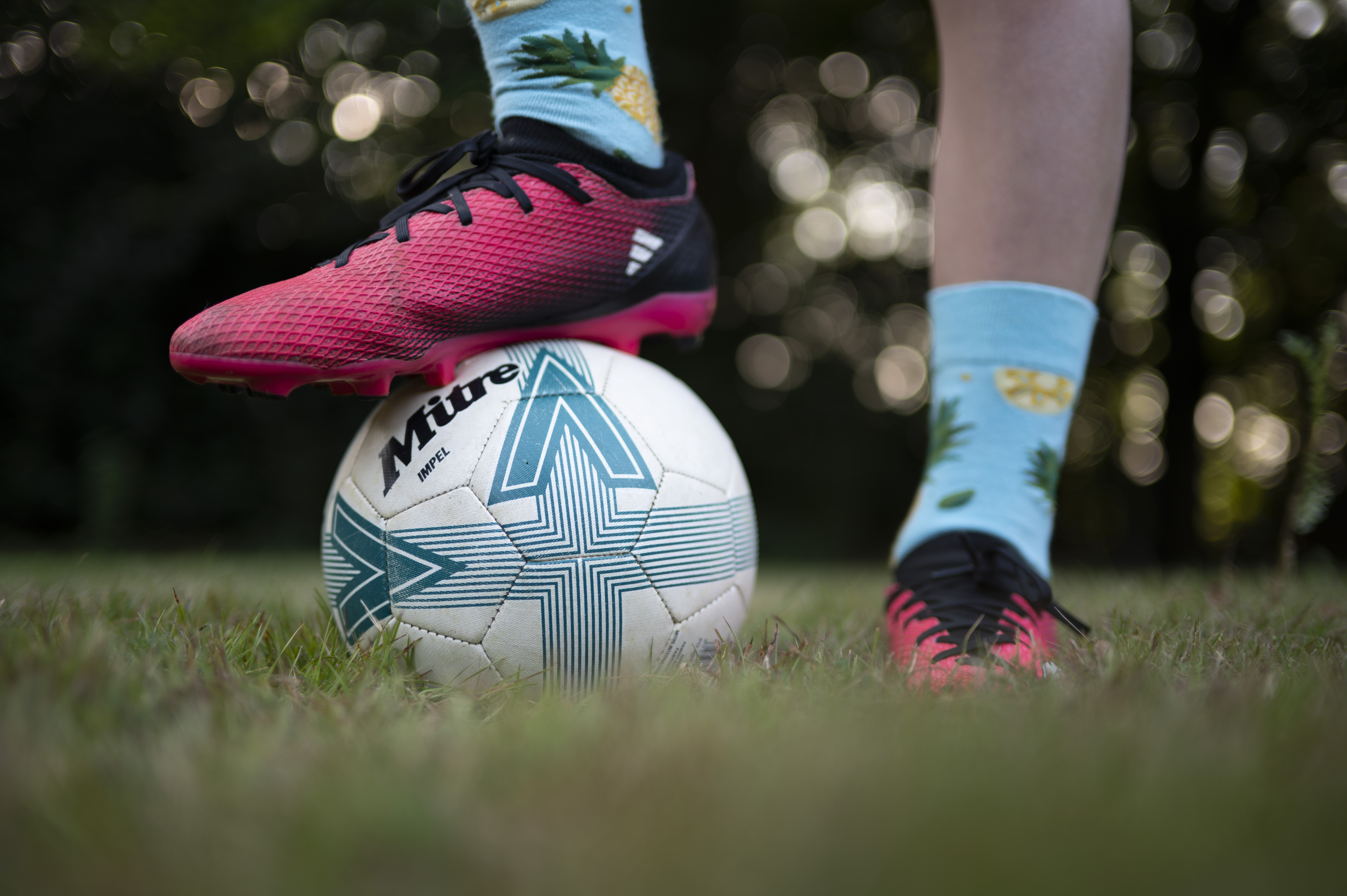 Closeup of a footballer's feet, with one foot standing on top of a ball