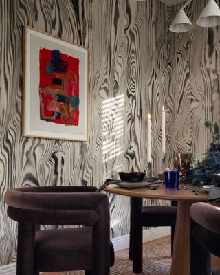 modern dining room with zebra print wallpaper. There is a round wooden dining table with modern, dark purple, velvet dining chairs