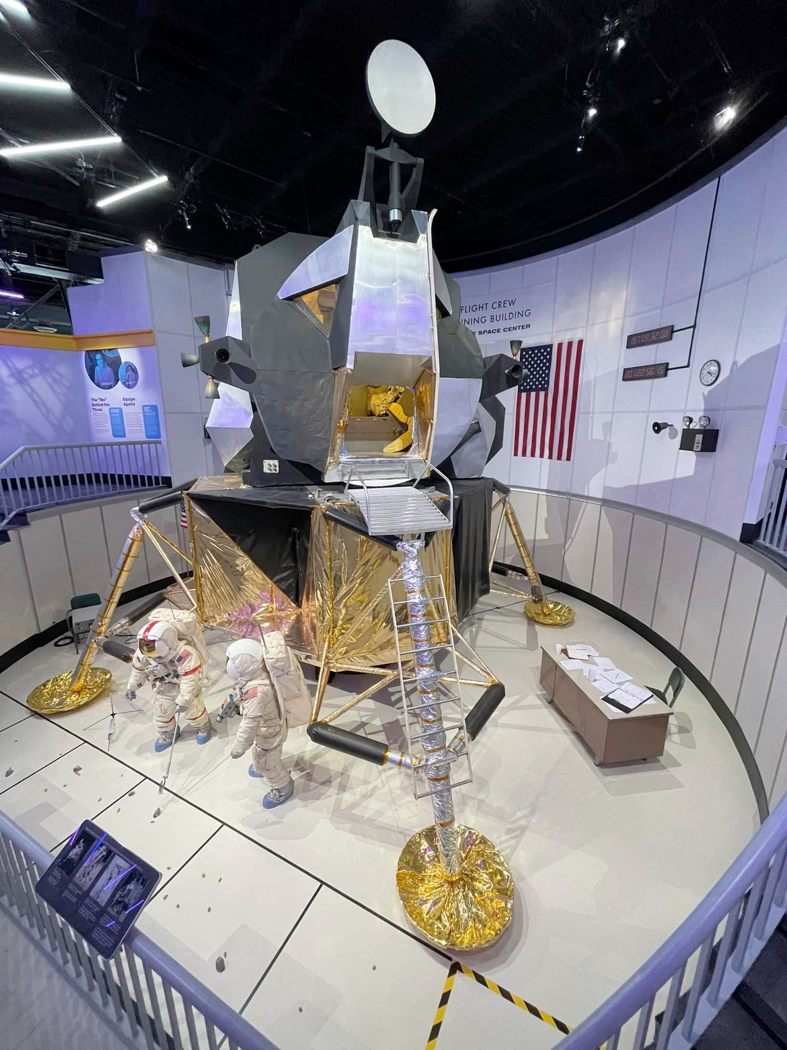 a model of a moon lander on display in a museum, with two spacesuit-wearing mannequins in front of it