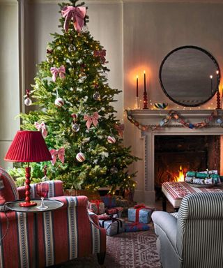 A large christmas tree in the corner of an eclectic, cozy living room with a lit fire