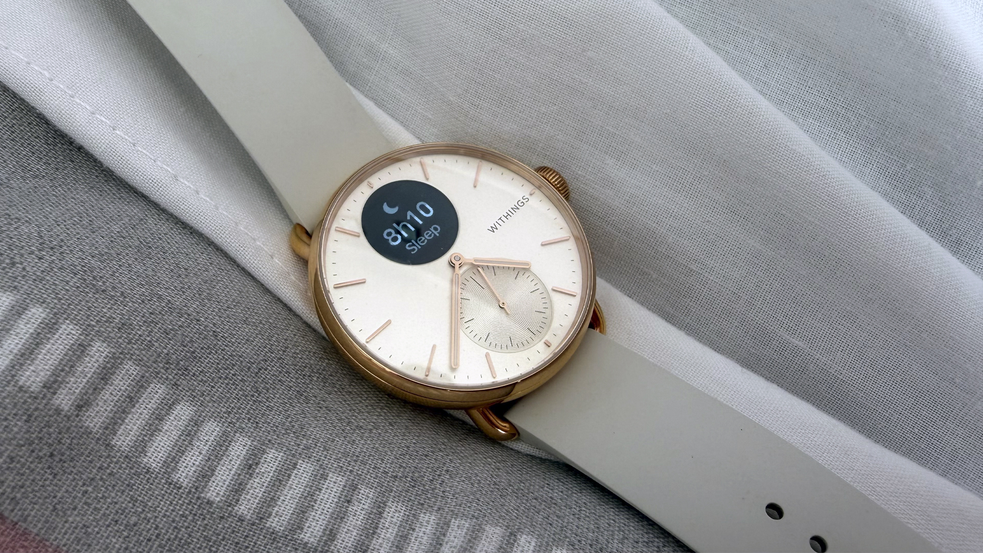 A closeup of the Withings ScanWatch 2 on a bed, with the display showing the reviewer's sleep time