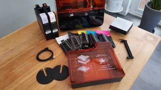 The Formlabs Form 3 surrounded by its accessories and resin tank box