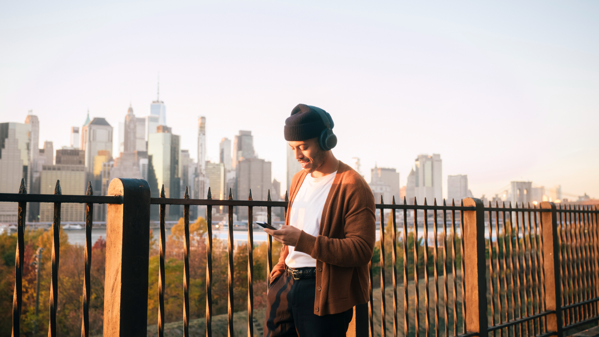 Person looking at their phone, wearing headphones, while outside.