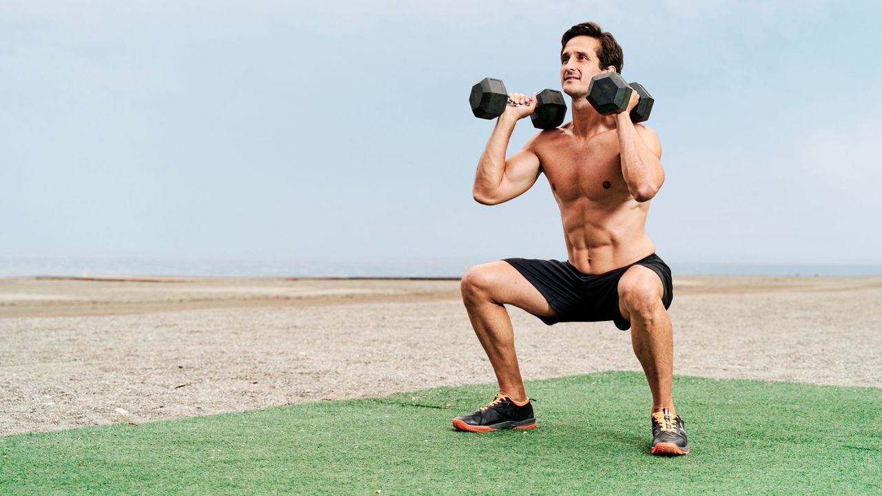 A man performing a dumbbell thruster as part of a full-body workout 