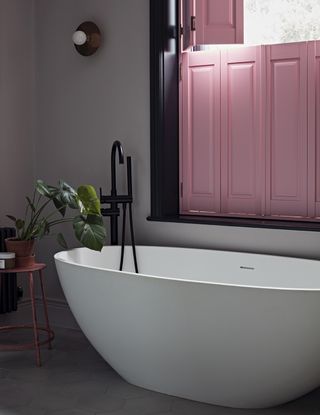 Bathroom with freestanding bathtub and pink shutters