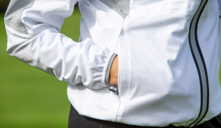 A golfer puts her hand in the pocket of the Abacus Women's Bounce Rain Jacket