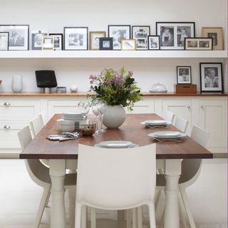 dining room with white wall and dining table and frames shelf