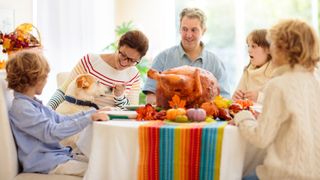Family sat around the dinner table with their dog enjoying Thanksgiving meal