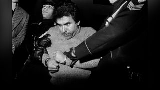  Black and white photograph of a man with handcuffed wrists and held by two police officers