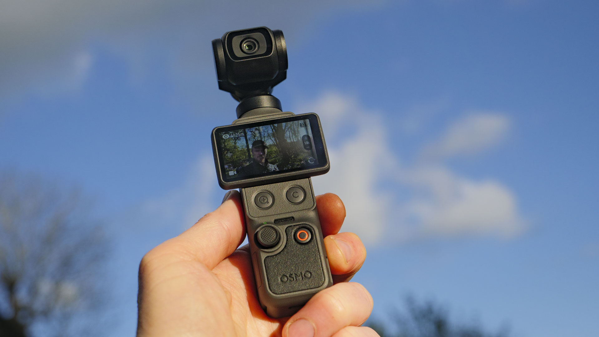 DJI Osmo Pocket 4 vlogging camera in the hand with sky background at golden hour