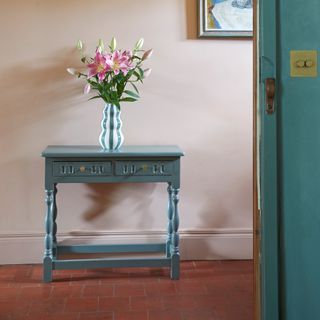 hallway with original terracotta tiles and blue side table with vase of lillies