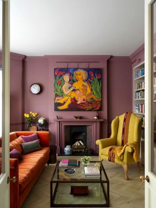 Purple living room with yellow armchair and orange sofa, light wood floor and black framed glass coffee table