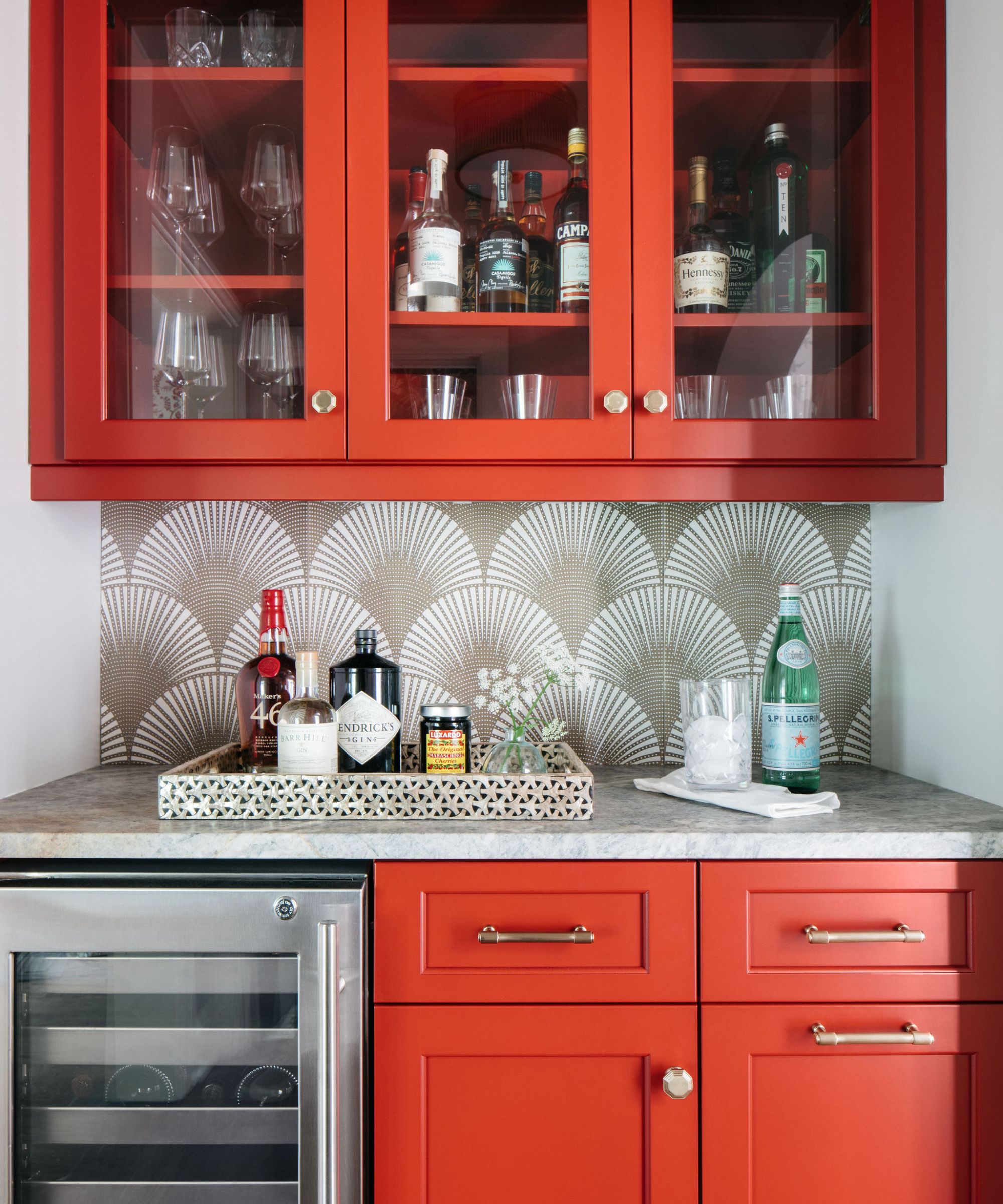 home bar with tomato red cabinets, neutral patterned splash-back and gray countertop