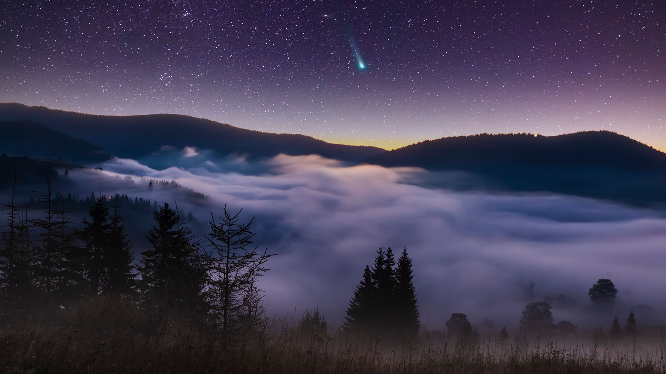 Comet above valley fog in amongst mountains