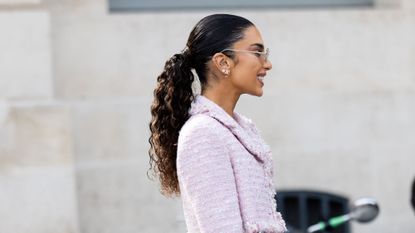 Woman wearing a pink tweed skirt suit, wearing her heritage brunette hair in a ponytail