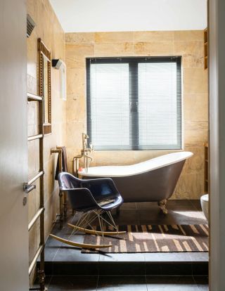 Warm toned stone tiled bathroom with freestanding bath