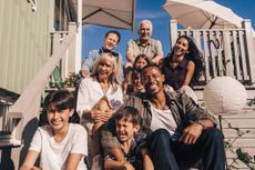Family sitting on the steps of a beach house.