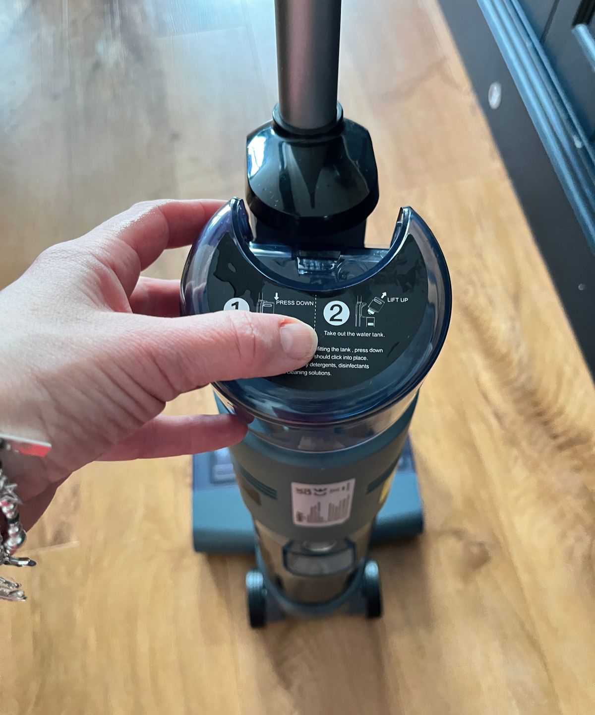 hand inserting clean water dispenser onto back of cleaner
