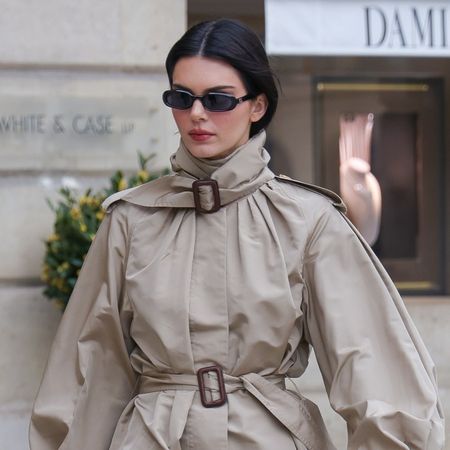 Kendall Jenner walks in Paris wearing a trench coat and carrying an Hermes Kelly bag with The Row kitten heels