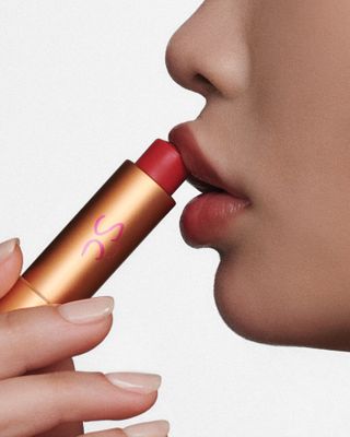 A model applying Augustinus Bader x Sofia Coppola tinted lip balm to her lips