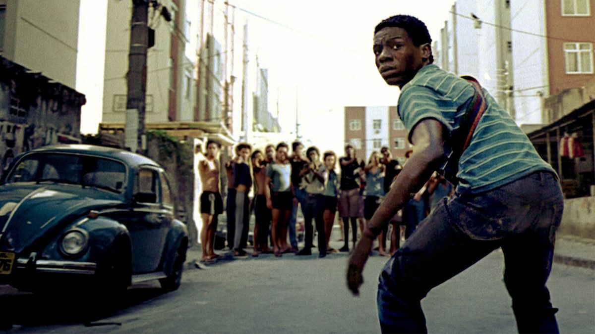 A boy stands in front of a group of kids in the street