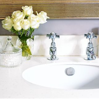 white washbasin with flower vase and chrome taps