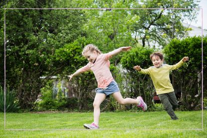 Two children running around in a garden with arms out wide