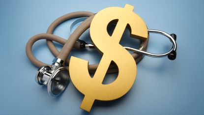 A large gold dollar sign rests on top of a stethoscope on a blue background