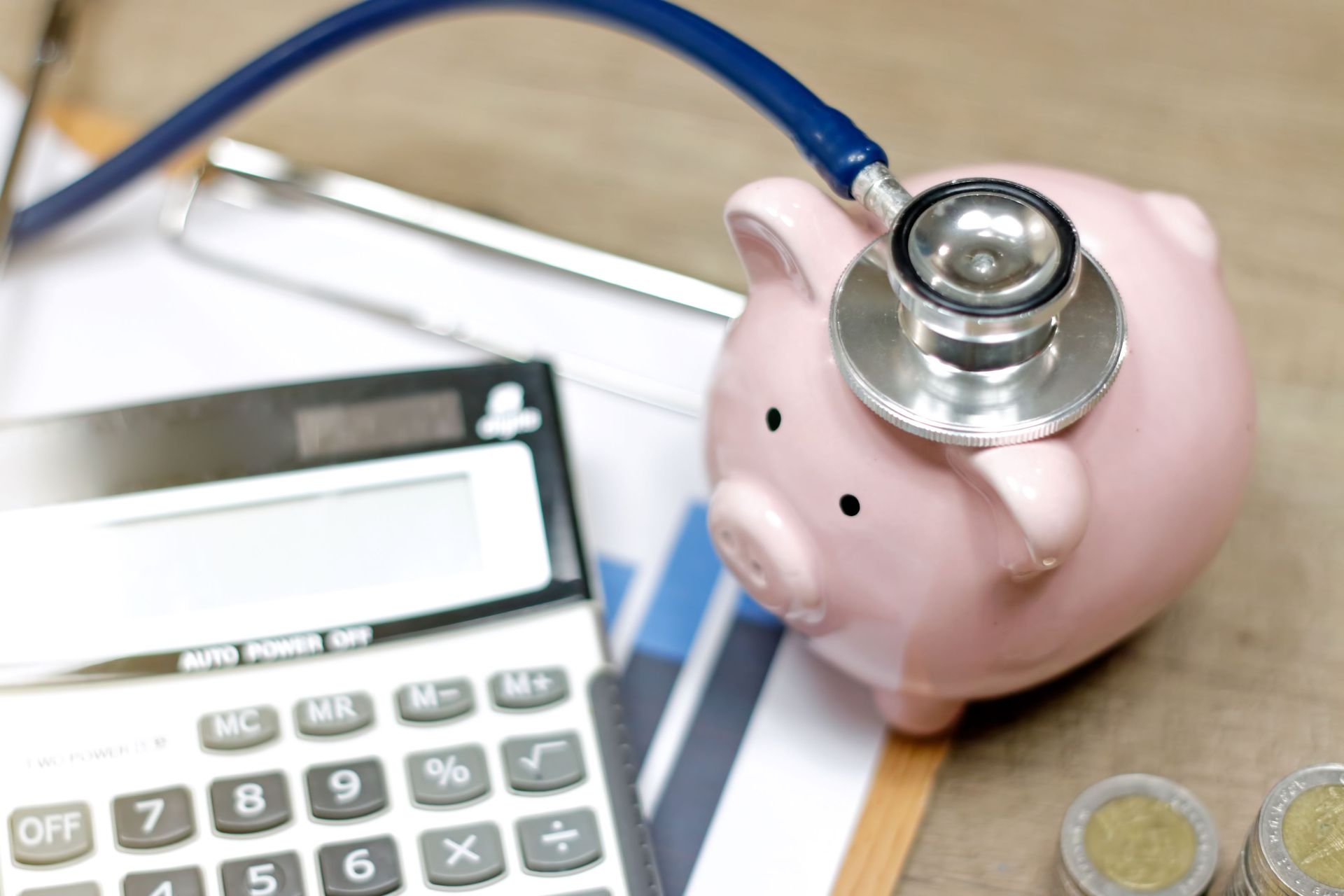 A picture of a piggy bank next to a calculator with a stethoscope.