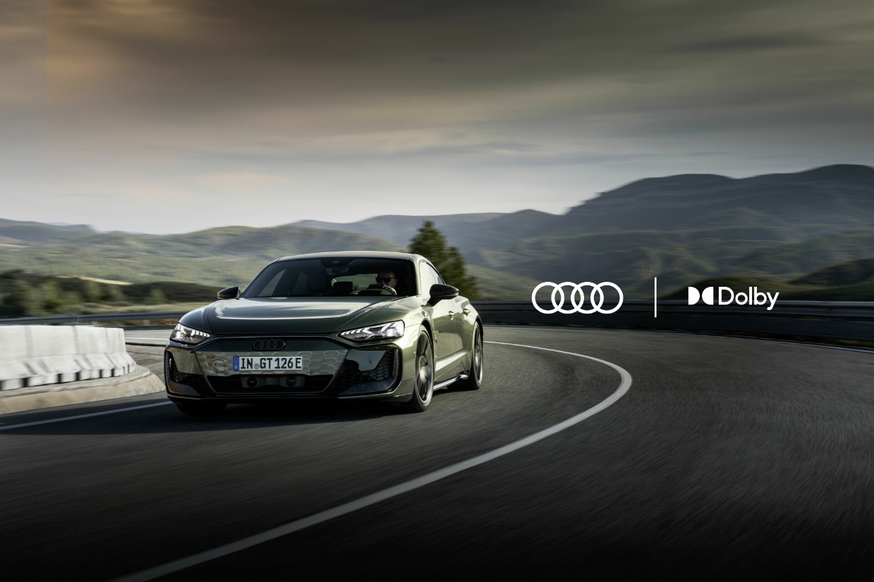 Audi e-Tron GT driving round a corner with Audi and Dolby logos next to it