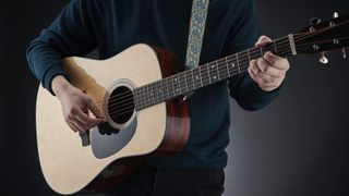 Beginner playing a Martin acoustic guitar standing up