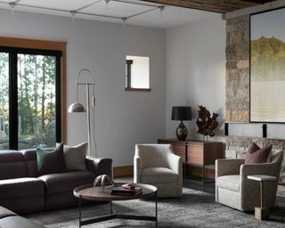 living room with exposed stone wall, gray sectional and off white chairs