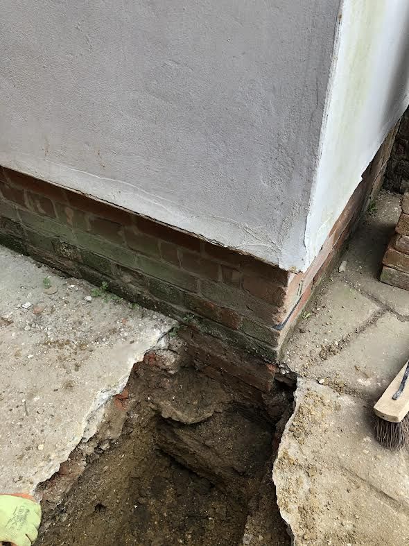 Hole showing a modern concrete foundation underneath a listed building