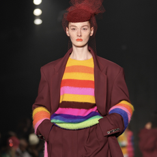 A model walks the runway for the Christopher John Rogers Collection 010 runway show at Brooklyn Navy Yard on June 07, 2022 in Brooklyn, New York wearing a rainbow striped sweater and maroon suit