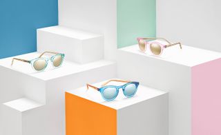 Three pairs of sunglasses positioned on white boxes with coloured panels