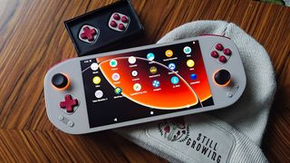 Mangmi Pocket Max handheld in retro beige next to beige beanie and modular button kit on woodgrain table.