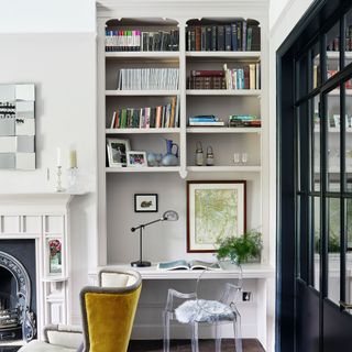 White bookshelf in living space with yellow velvet accent chair