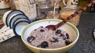 A bowl of ovrenight oats on a countertop in front of jars of ingredients